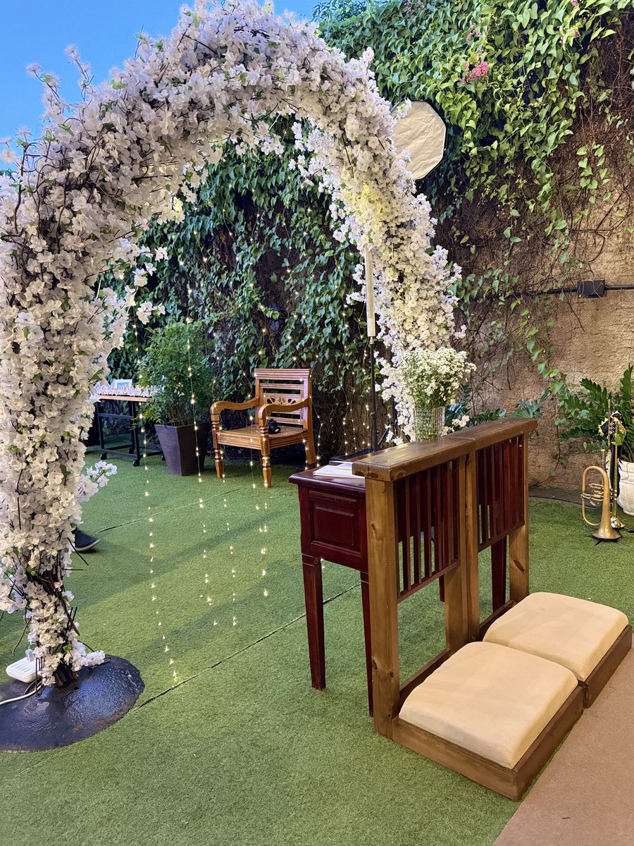 Cerimônia montada com arco floral, cortina de luz e instrumento musical