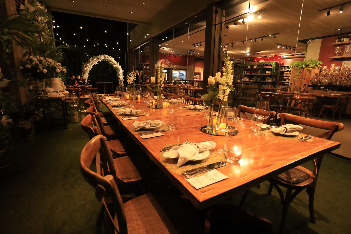 Salão decorado do Canto do Vinho com mesa de jantar e arco floral